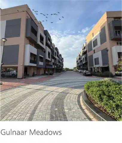 Gulnaar Meadows luxury residential entrance in Zirakpur with paved driveway, landscaped greenery and modern apartment facades