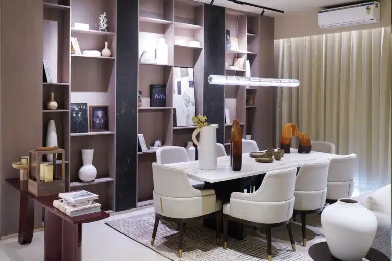 Gulnaar Zenium 4+1 BHK dining room interior with marble dining table, cushioned chairs, decorative vases and wall shelving