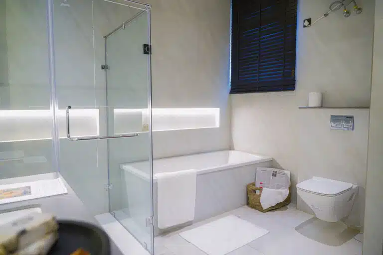 Gulnaar Zenium modern bathroom with freestanding bathtub, frameless glass shower, wall-hung toilet and marble-look tiles